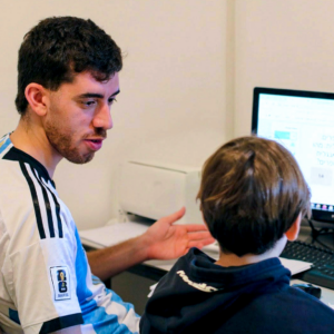 Math tutor explains at a computer while a student follows on the monitor during a private math lesson.